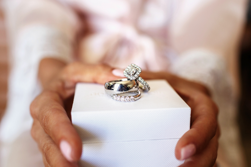 A woman holds a white box in front of her that has several different styles of bridal rings displayed on it. 
